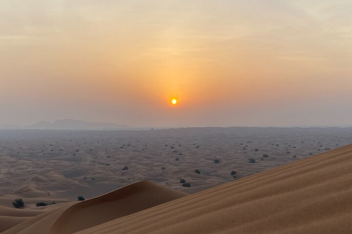 Awakening to the soft hues of dawn explore the vast desert landscapes with a quad bike ride sandboarding and a memorable camel journey through timeless Dune realms.